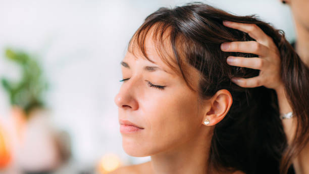Woman with eyes closed having her hair adjusted by another person indoors.