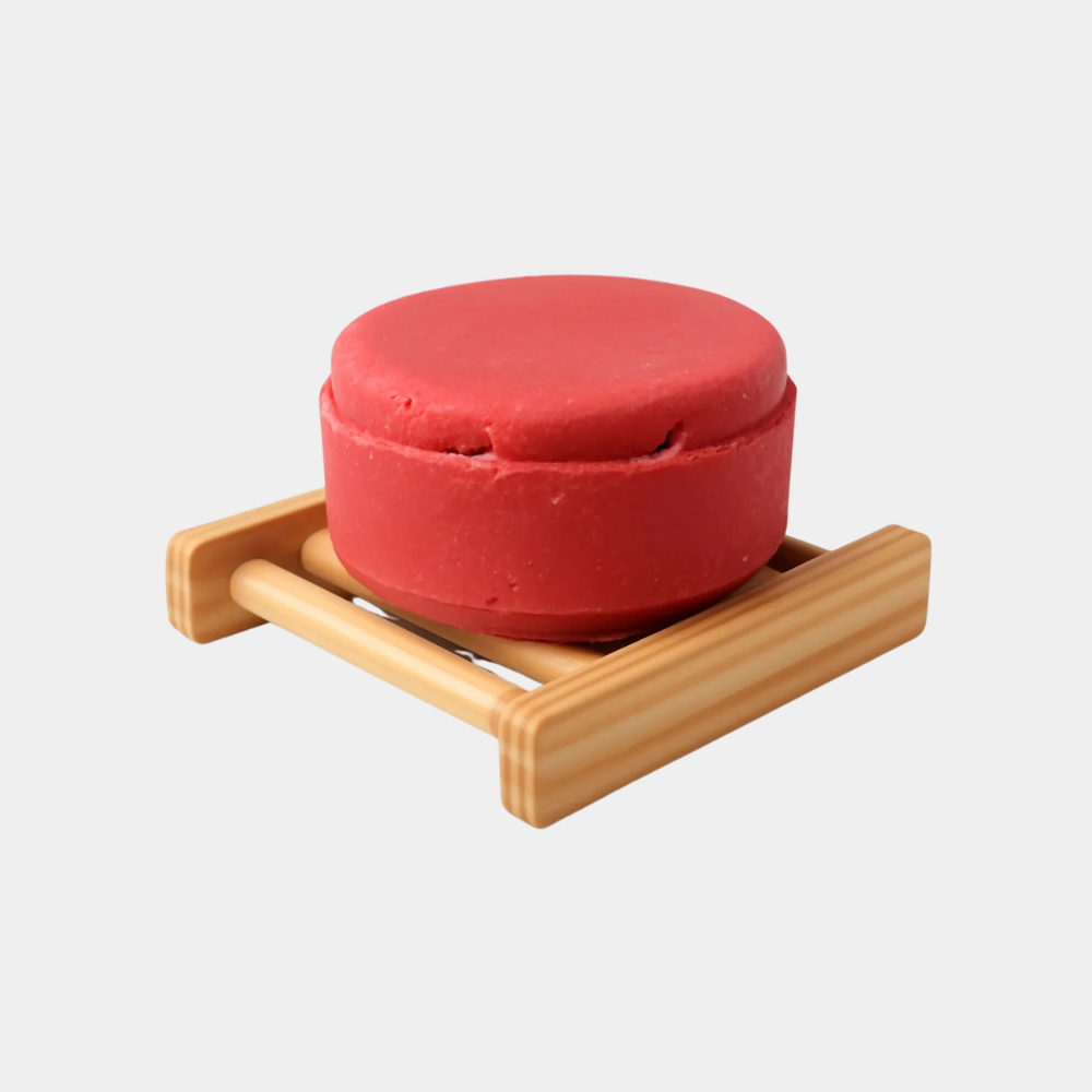 Red ceramic bowl on a wooden stand against a white background